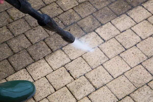 Pressure washing a paved concrete patio